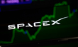 The SpaceX logo is displayed on the screen of a smartphone placed on a reflective surface...