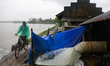 A man rides his bicycle along a tributary of Vembanad Lake while water is pumped from a fi...