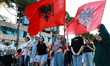 Young women wave Albanian flags during a demonstration against a proposed luxury tourism d...
