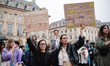 Two women hold signs reading, ''If a child's word isn't enough, who will protect them?'' a...