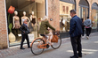 A woman rides an orange city bicycle past a fashion boutique in Ferrara, Italy, on April 6...
