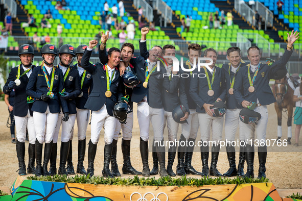 Players of Germany, France and Australia (from L to R) celebrate at the awarding ceremony of the equestrian eventing team competition at the...