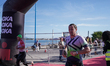 Athletes run barefoot through the IRONMAN arch on the way to the transition zone after com...