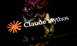 The Claude Mythos logo is displayed on the screen of a smartphone placed on a reflective s...