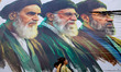 People walk past a billboard featuring the portraits of (right to left) Iran's new Supreme...