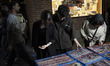 Iranian youths look at jewelry displayed on a sidewalk by a vendor in downtown Tehran, Ira...