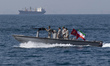 Iranian Navy soldiers are seen on an armed speed boat near a commercial vessel in the Pers...