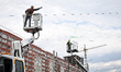 Municipal workers use aerial work platforms to install protective nets over the road to sh...