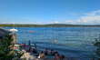 Visitors relax, swim, sunbathe, and gather along the shoreline and piers at Lake Starnberg...