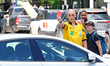 A person dressed as a FIFA referee displays a red card to a motorist blocking traffic and...