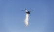 A helicopter drops water as Los Angeles Fire Department crews work to contain a fire that...