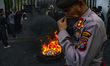 A police officer from the Pelopor unit covers his face to shield against thick smoke as pr...