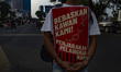 A protester carries a red placard reading ''Bebaskan Kawan Kami! Penjarakan Pelanggar HAM'...