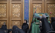 Iranian women sit beside a religious symbol while participating in Tasua commemorations ne...