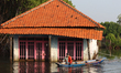 A fisherman navigates his boat near a residential house partially submerged by seawater in...
