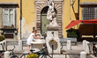 A woman cools her hands and refreshes herself at a historic public fountain during hot wea...