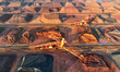 Large machinery piles up inventory of imported iron ore just unloaded from a cargo ship at...