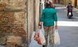 A woman carries shopping bags along a narrow street in the historic center of Siena, Tusca...