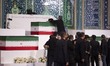 An unidentified man places a black turban on a coffin during a ceremony honoring the remai...