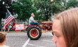 A man drives a vintage Farmall tractor pulling a sign during the 4th of July Parade in Eva...