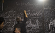 A pro-government supporter writes a slogan on a partition wall separating male and female...