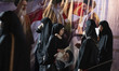 Veiled Iranian women walk past a banner depicting portraits of late and current Supreme Le...