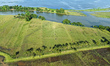 A drone view captures the mosaic of grazing fields, waterways, and the expansive waters of...