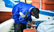  Fisherman holds a fresh fish during trading day at Pasar Bisik in Kuala Muda near border...