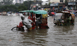 Rickshaw pullers wade through a waterlogged street after heavy monsoon rains in Dhaka, Ban...