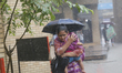 A woman holds her child as she walks towards a hospital in the monsoon rain in Dhaka, Bang...
