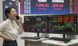 A Korea Exchange (KRX) employee monitors stock market data on trading screens inside the K...
