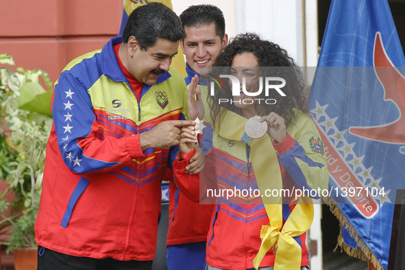 Venezuelan President Nicolas Maduro (L) and BMX cycler Stefany Hernandez (R) take part in the ceremony to receive the athletes of the Venezu...