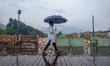 A man holding an umbrella walks on a wooden bridge over the Jhelum River as water levels r...