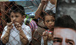 Filipino children look from behind a grill fence as Kevin Love (unseen) pays a visit at th...