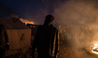 A Migrant stand in the Calais Jungle in front of a hut which is set on fire  in Calais, Fr...