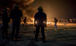 French riot police advance through tear gas and smoke from a fire to disperse migrants thr...