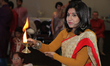 Bengali Hindu woman holds a lamp to bless devotees while assisting in prayers during the D...