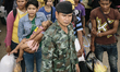 Cambodian migrants wait for instructions from soldiers before crossing the border to retur...