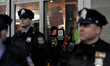 Police stand by at the doors as a small group of protestors occupies a space inside as tho...
