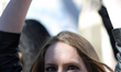 Kate Hamberer, of NY, holds up her hands in cuffs as she stands with other protestors duri...