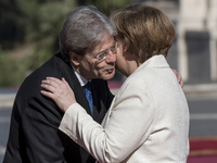 Italian Prime Minister Paolo Gentiloni, left, greets German Chancellor Angela Merkel during arrivals for an EU summit at the Palazzo dei Con...