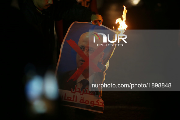 Palestinian youths burn  a crossed poster depicting Prime Minister Rami Hamdallah during a protest against the Israeli blockade of the Gaza...