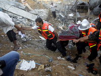Rescue workers carry the body of a member of al-Najar family, after removing it from under the rubble of their home following an Israeli air...