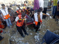 Rescue workers carry the body of a member of al-Najar family, after removing it from under the rubble of their home following an Israeli air...