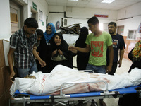 A Palestinian relatives mourn over the body of man from the family-Najjar, in the hospital morgue after a an Israeli air strike on their hou...