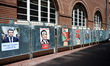 Electoral campaign posters near a polling station,  People come to vote at the Capitole's...