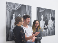 Young people take a selfy in front of photographs 'Sisters' and 'Sisters 2' by a group of artists  'Lodz Kaliska' - a part of 'Art in Art' n...