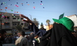 A Palestinian woman showers masked militants of Ezzedine al-Qassam Brigades, Hamas's armed...