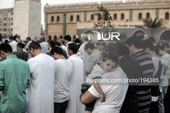 Children attend Eid al-Fitr prayers with their father outside a mosque in Giza July 28, 2014. Eid al-Fitr marks the end of the Muslim holy m...