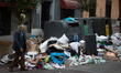A man walk past piles of rubbish dumped around recycle containers during the fourth day of...